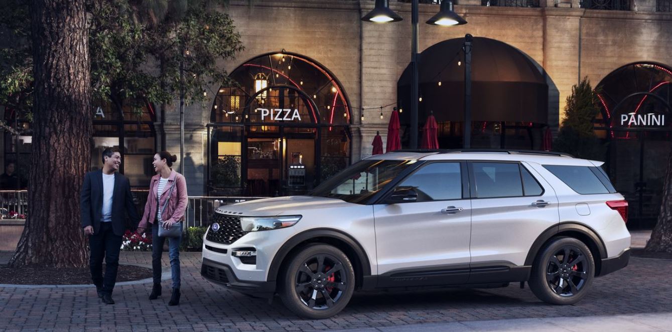 Image of a couple walking toward a white 2020 Ford Explorer in the city.
