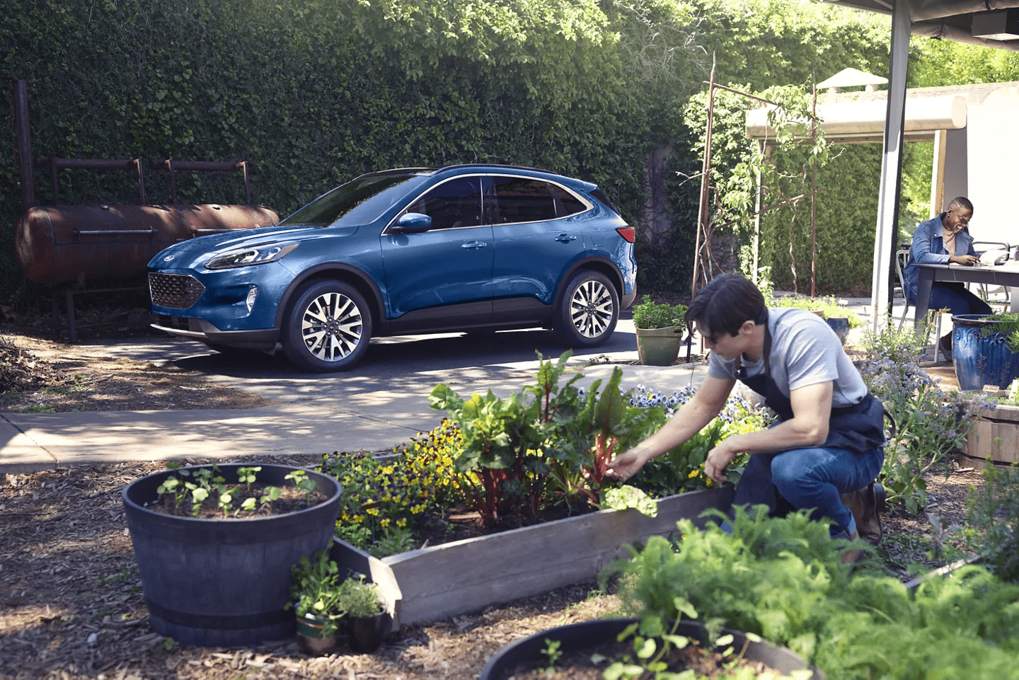 A blue 2022 Ford Escape parked while a family gardens